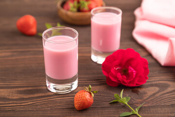 Sweet strawberry liqueur in glass on a brown wooden background. side view, selective focus