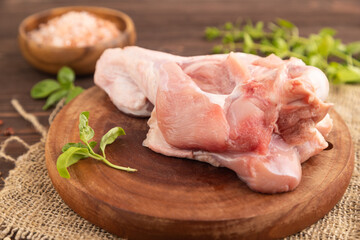 Raw turkey wing on a wooden cutting board on a brown wooden background. Side view, selective focus.