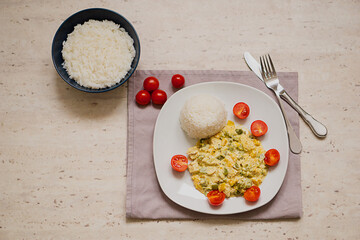 Hot dish of rice, meat and vegetables, homemade and served on a plate on white background.