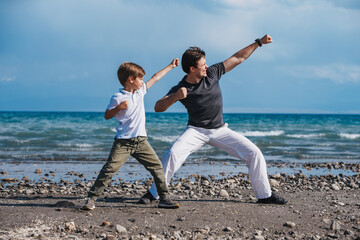 Father teaches his son martial arts on the beach - 624939933