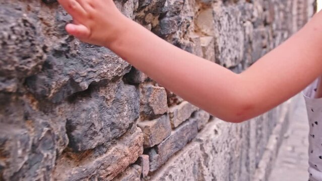 Young Caucasian Girl Sliding Her Hand Over Old Wall in Italian Medieval Renaissance Stronghold City Touching Red Clay Bricks