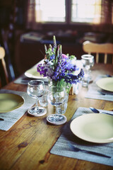 2 wine glasses with lupines on the table in a wooden cottage
