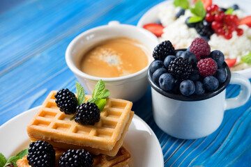 Blackberry waffles with blueberries and a cup of coffee for breakfast