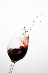 glass of red wine in motion with the wine flowing out of the glass