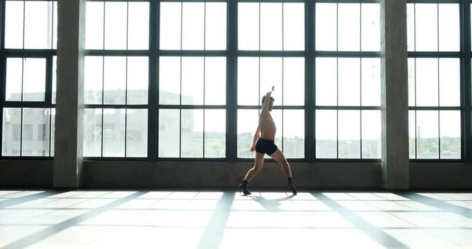 Caucasian dancer as he unleashes his talent in a jazz funk performance on high heels. His flawless technique, expressive movements create an enchanting spectacle against of a window.