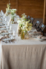 beautiful table setting with flowers and cutlery on wooden table at wedding or dinner. stylish tablewear decorations