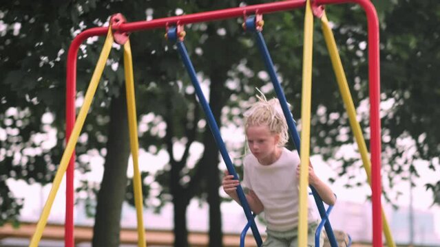 Girl swinging on swing in park, child having fun , playing on outdoor public playground, kids play on school or kindergarten yard, active kid on colorful swing, healthy summer activity for children