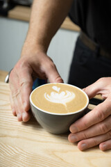 Fototapeta na wymiar Barista hands serving coffee latte with art