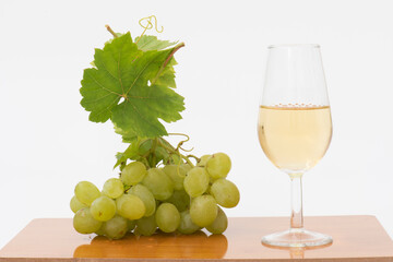 Una copa de vino blanco junto a un racimo de uvas