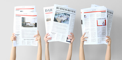 Female hands with newspapers on light background
