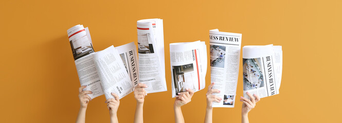 Female hands with newspapers on orange background - obrazy, fototapety, plakaty