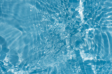 Blue water with ripples on the surface. Defocus blurred transparent blue colored clear calm water surface texture with splashes and bubbles. Water waves with shining pattern texture background.