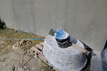 Closeup of Construction Equipment (Plastic mixing bowl, black plastic can, plastic scoop, spade) placed next to the cement wall on the construction site work at Bangkok, Thailand.