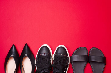 Variety of modern black women's shoes on a bright reddish pink background with copy space. Stylish...