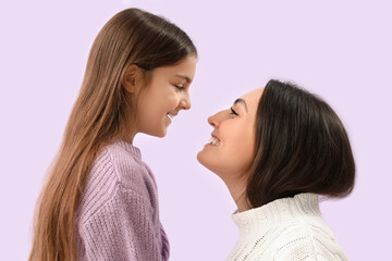Little girl and her mother in warm sweaters on lilac background, closeup