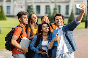 Portrait of happy multiethnic students talking selfie on smartphone outdoors