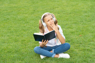 Naklejka na ściany i meble education through self reading boring book. audio book or ebook. teen girl lifestyle. music education while listening. lifestyle of teenager girl outdoor. bored teen girl in music headphones