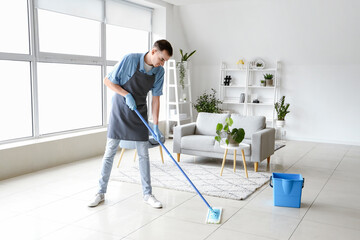 Male janitor mopping floor in living room