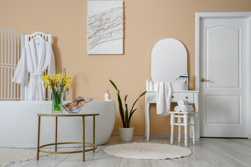 Interior of bathroom with bathtub, dressing table and narcissus flowers