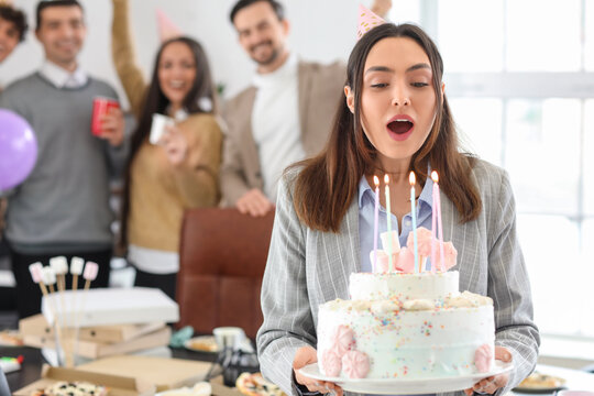 Young woman with Birthday cake making wish at party in office