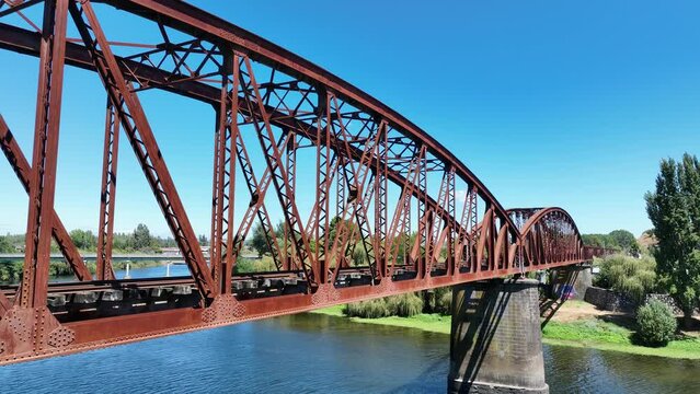 Puente de tren en forma de arco de metal oxidado sobre un r&iacute;o grabado con dron dji mavic 3 4k 60fps