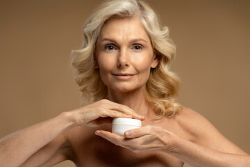 Closeup portrait of Caucasian blonde woman holding a jar with anti-aging body cream