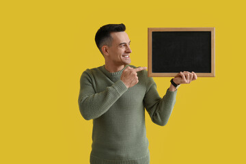Male teacher pointing at chalkboard on yellow background