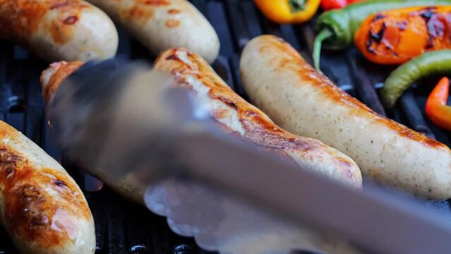 Cooking roast juicy bratwurst sausages on the barbecue grill. Close up.