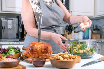 Cooking Caesar salad. Cook adds grated parmesan to glass bowl with salad in a home kitchen.