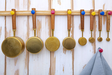 Copper measuring cups with wooden handles hang on the wall in the kitchen.