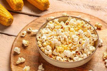 Bowl with tasty popcorn on white wooden background