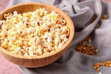 Bowl with tasty popcorn on pink background, closeup