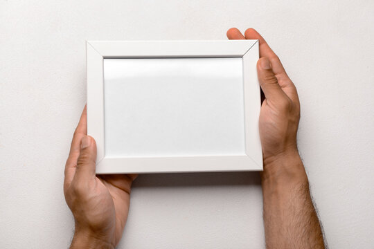 Man holding blank photo frame on white background