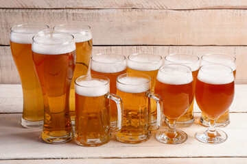 Glasses and mugs of cold beer on light wooden background. Oktoberfest celebration