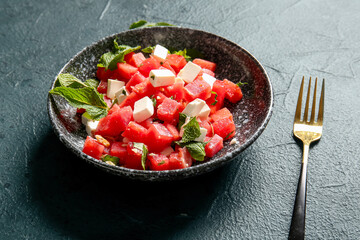 Bowl of tasty watermelon salad on blue background
