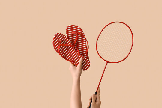 Female hands with flip flops and badminton racket on beige background