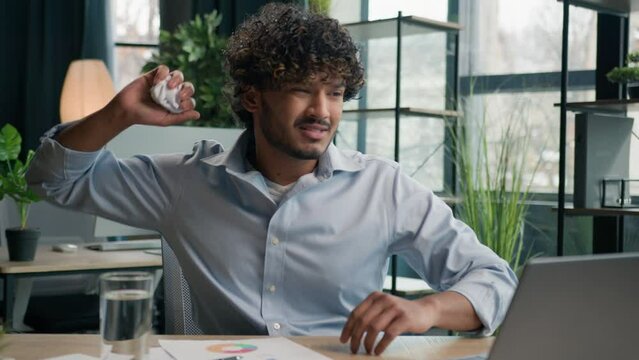 Upset anxious businessman Arabian Indian man working at office write graphics business paperwork no ideas crisis mistake wrong papers difficult work burnout failure crumpling sheet of paper throw away