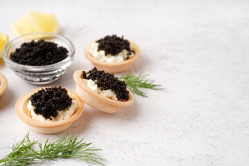 Fototapeta na wymiar Tasty tartlets with black caviar on light background