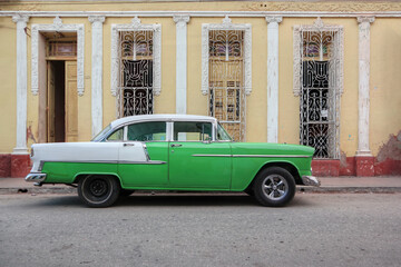 A green Cuban taxi in front of a light orange facade in the town of Trinidad 