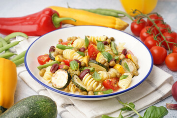 Bowl of tasty pasta salad with tomatoes and basil on white background