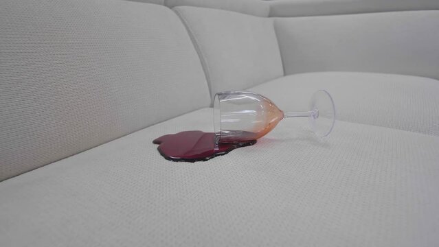 a glass of red wine spilled on a new beige sofa