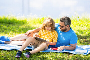 son with father bonding in summer. family education of father and son kid. Father shapes son education with book tablet. Father and son relax in park. childhood school education. quality time reading