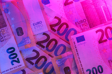 Two hundred euro in purple neon light. Money colored background.Inflation of money in the EU...