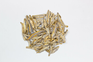 Dried anchovies on a white background. Isolated. Сlose-up. Top view. Small dried anchovies on salt on the table. Salted sea fish for beer. Seafood snack. Dry anchovy.