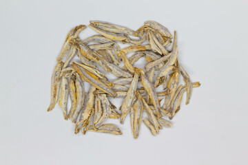 Dried anchovies on a white background. Isolated. Сlose-up. Top view. Small dried anchovies on salt on the table. Salted sea fish for beer. Seafood snack. Dry anchovy.