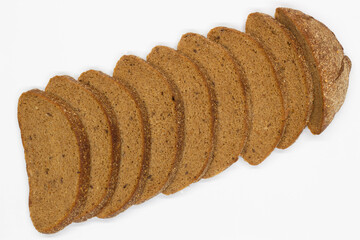 Sliced black bread. Dark rye bread with cumin cut into even pieces on a white background. Wheat black bread on the table. Isolated. Bran from grain. Healthy food. Vegetarian food. Ecological friendly