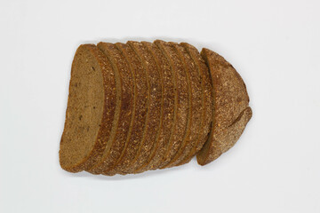 Sliced black bread. Dark rye bread with cumin cut into even pieces on a white background. Wheat black bread on the table. Isolated. Bran from grain. Healthy food. Vegetarian food. Ecological friendly