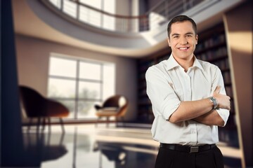 Young happy business man with arms crossed at office