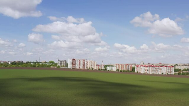 Aerial footage of the suburbs against the background of a green field and a beautiful blue nema with clouds