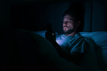 Man using smartphone in bed at night. Internet addiction